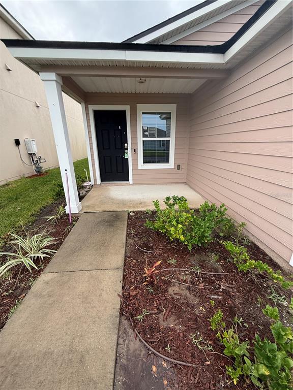 A covered front porch leads to a black front door next to a single window — 754 GRAND RESERVE DRIVE, BUNNELL, FL