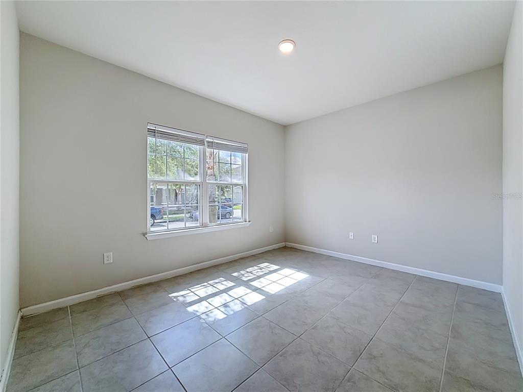 An empty room features light-colored walls, large floor tiles, and a window with blinds — 5754 SURPRISE LILY DRIVE, WINTER GARDEN, FL