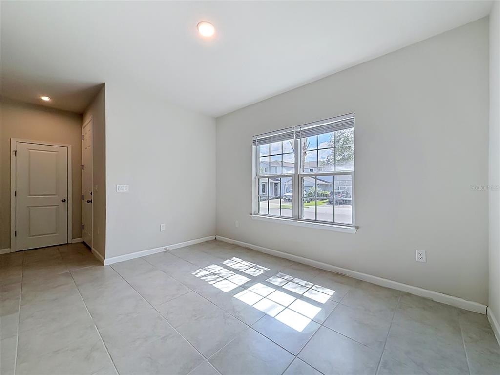 An empty room features light-colored tile flooring, neutral walls, and a window with blinds — 5754 SURPRISE LILY DRIVE, WINTER GARDEN, FL