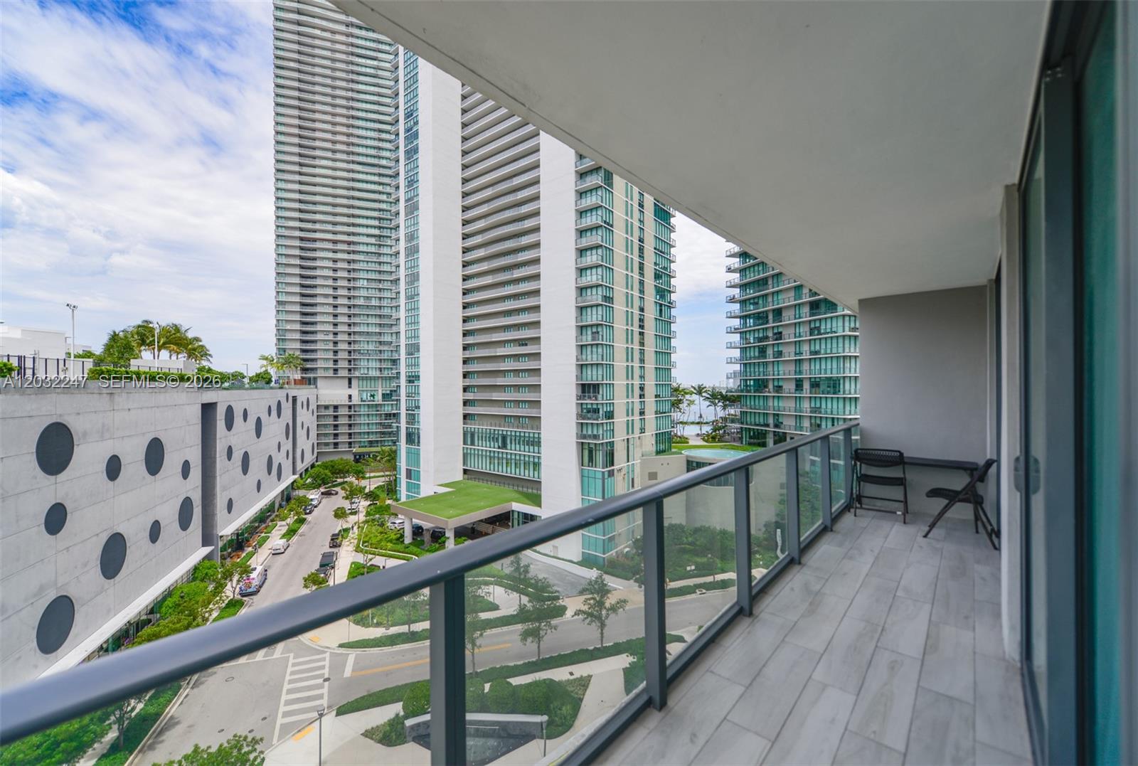 A balcony with a glass railing overlooks a street and several tall residential buildings — 501 NE 31st St # 601, Miami FL 33137, MIAMI, FL