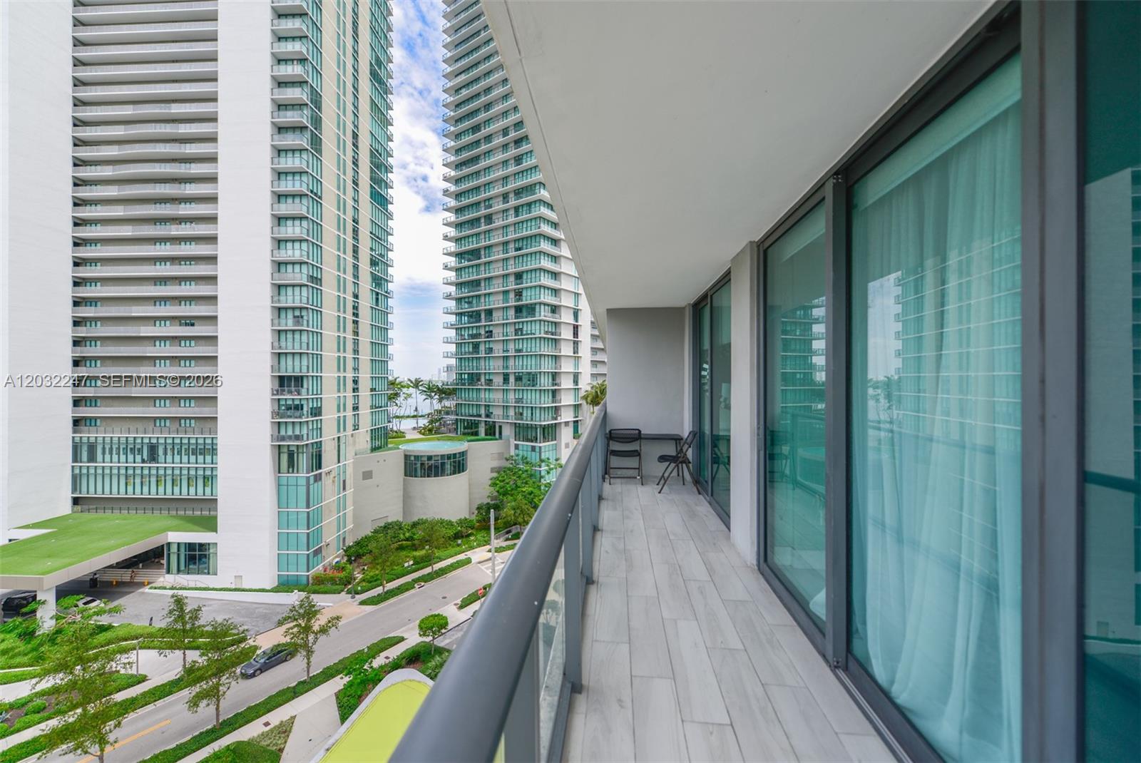A balcony with light-colored tile flooring overlooks a street and tall residential buildings — 501 NE 31st St # 601, Miami FL 33137, MIAMI, FL
