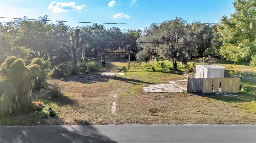 An elevated view of a grassy, partially cleared lot with trees and a small shed — 23 VIOLET STREET, PLANT CITY, FL