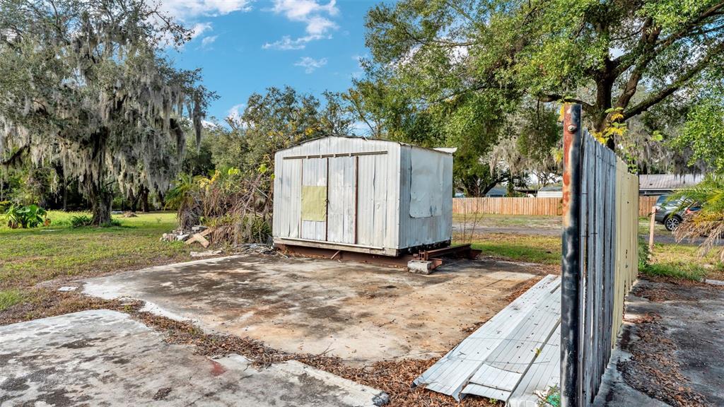 A small metal shed sits on a concrete slab next to a wooden fence — 23 VIOLET STREET, PLANT CITY, FL