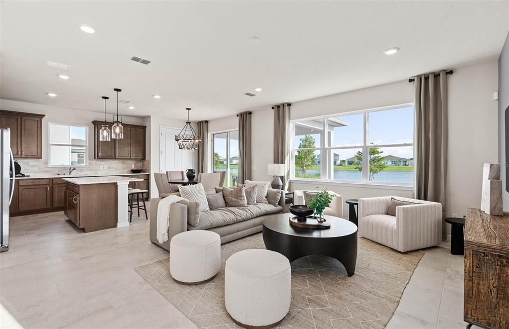 An open-concept living room and kitchen featuring brown cabinetry, a lake view, and neutral furniture — 1424 HAMILTON WAY, LAKE ALFRED, FL