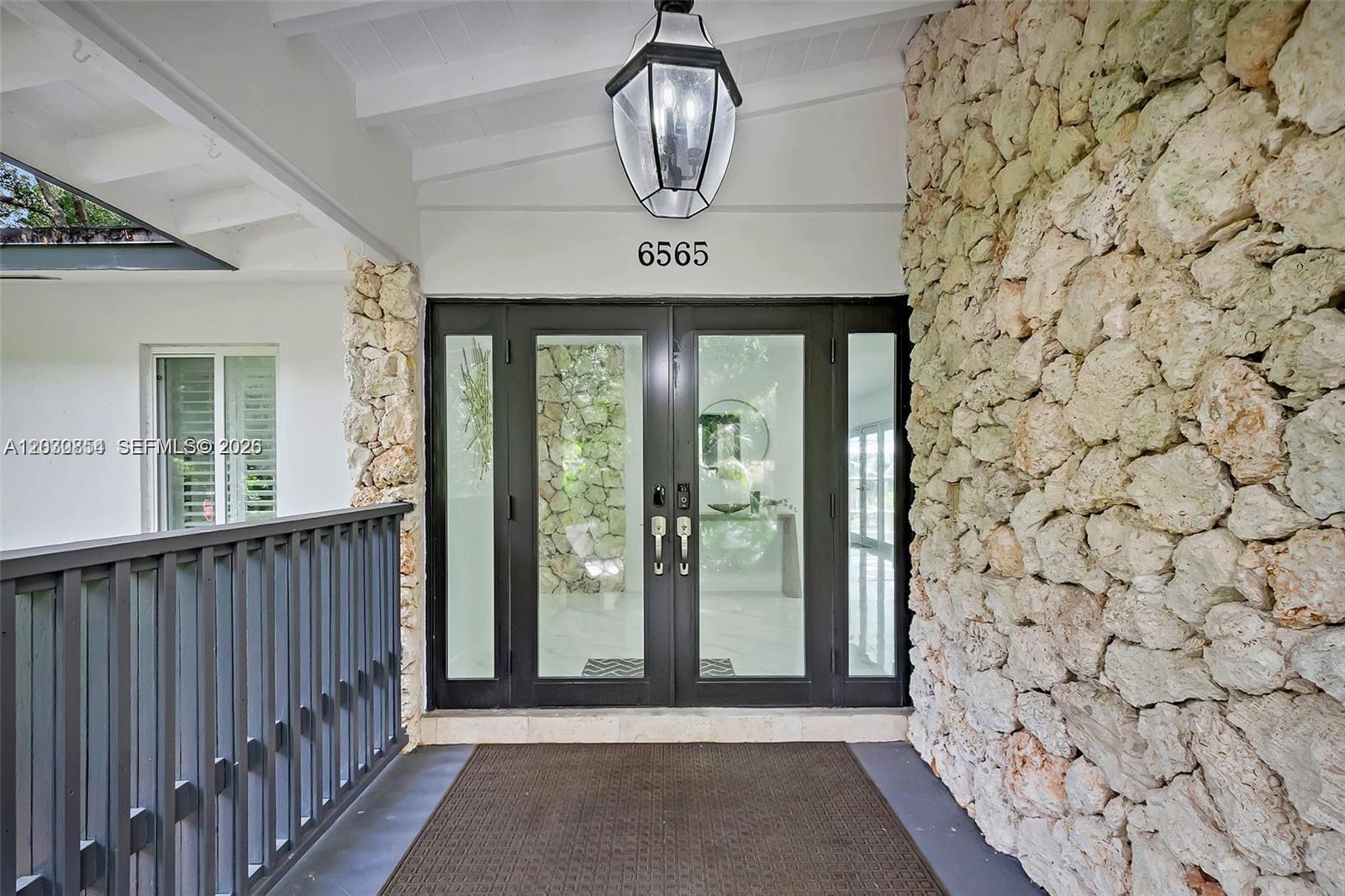 The entrance features double glass doors flanked by stone walls under a covered porch — 6565 SW 134th Dr, Pinecrest FL 33156, PINECREST, FL
