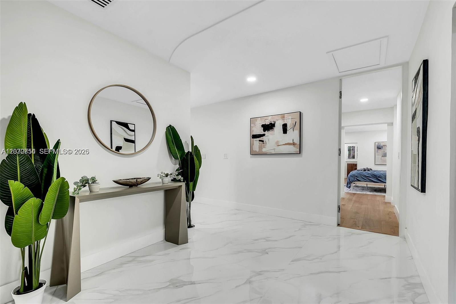 A white hallway features marble flooring, a console table, a round mirror, and wall art — 6565 SW 134th Dr, Pinecrest FL 33156, PINECREST, FL