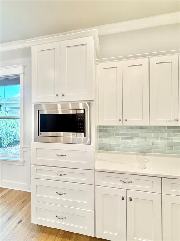 A kitchen features white cabinets, a built-in microwave, and a light blue subway tile backsplash — 2537 NW 48TH TERRACE, GAINESVILLE, FL