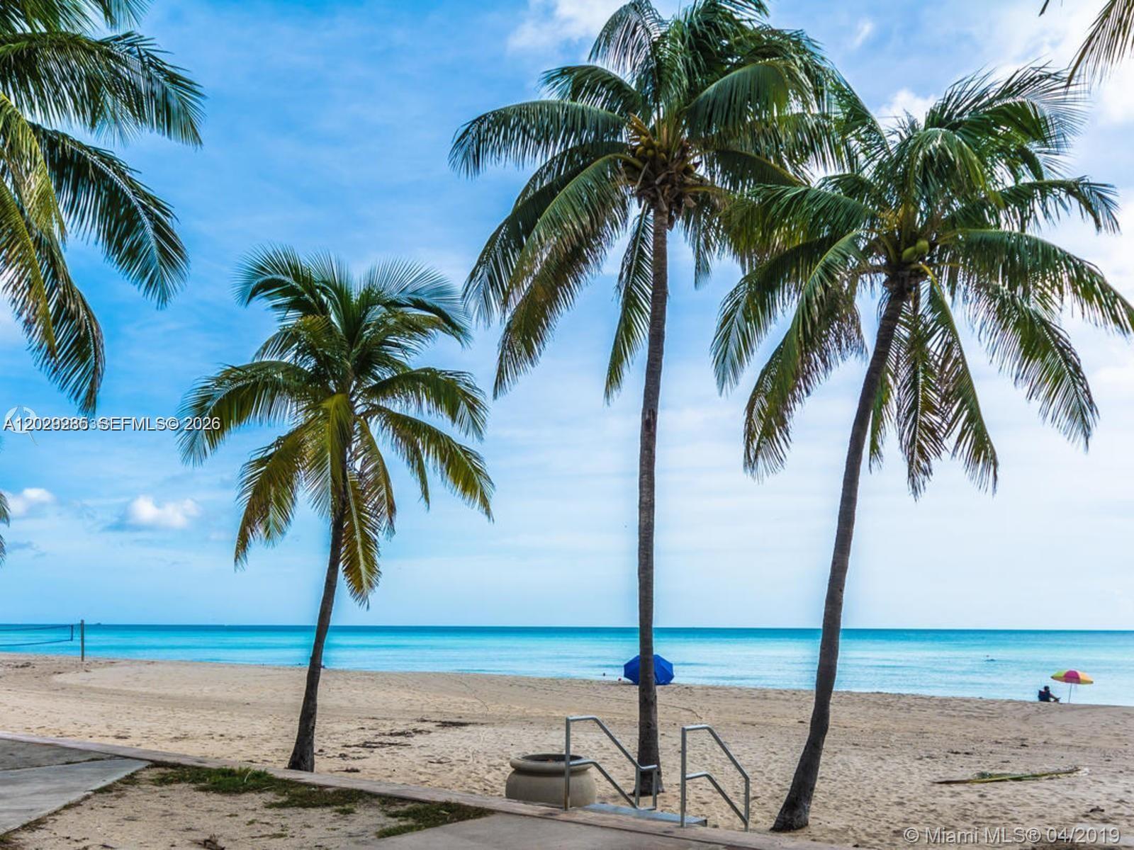 A sandy beach with palm trees, a blue umbrella, and a small staircase — 2101 S Ocean Dr # 306, Hollywood FL 33019, HOLLYWOOD, FL