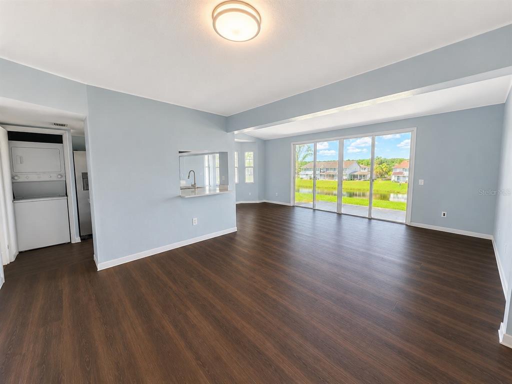 A living room with light blue walls, dark wood-look flooring, and sliding glass doors to water — 872 CARIBBEAN DRIVE, DAVENPORT, FL