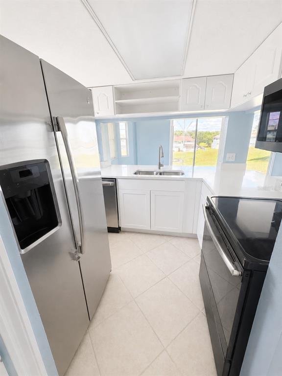 A kitchen features white cabinets, stainless steel appliances, white countertops, and light-colored tile flooring — 872 CARIBBEAN DRIVE, DAVENPORT, FL