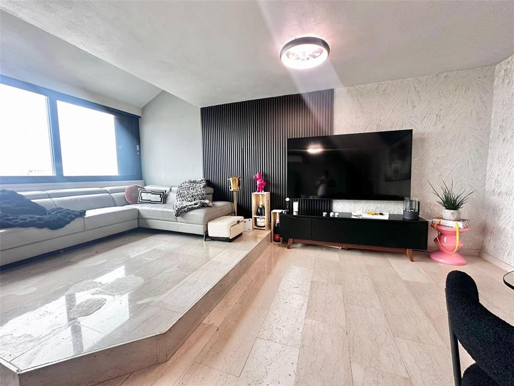 A living room features a raised marble platform, a sectional sofa, and a slatted accent wall — 1261 LUIS VIGOREAUX AVENUE UNIT 18D, GUAYNABO, PR