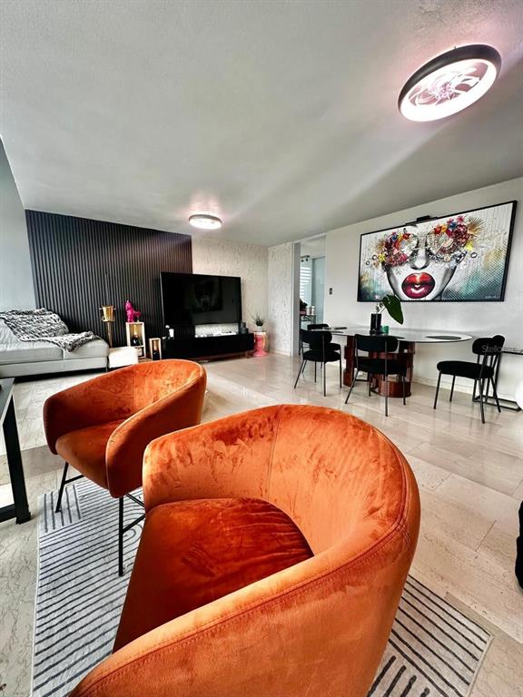 A living and dining area features orange velvet chairs, a large wall painting, and tile flooring — 1261 LUIS VIGOREAUX AVENUE UNIT 18D, GUAYNABO, PR