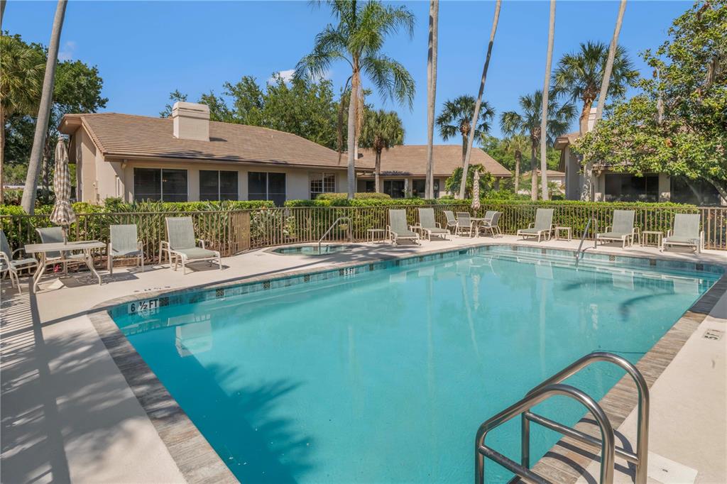 A swimming pool with lounge chairs and palm trees sits in front of a house — 4424 HIGHLAND PARK UNIT 5, SARASOTA, FL