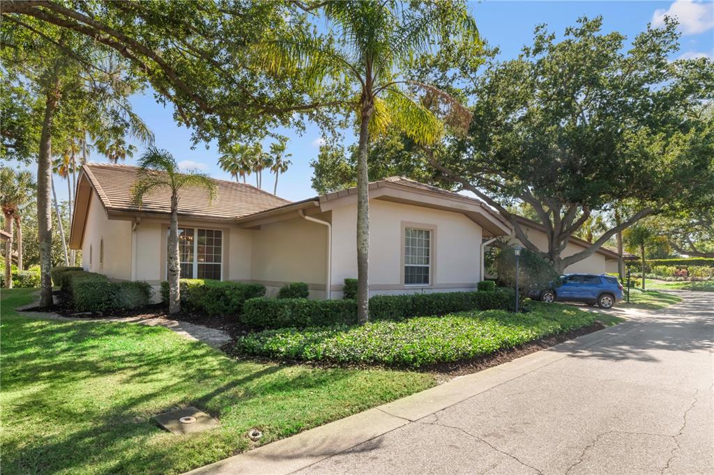 A single-story house with a beige exterior, tile roof, and landscaping sits beside a driveway — 4424 HIGHLAND PARK UNIT 5, SARASOTA, FL
