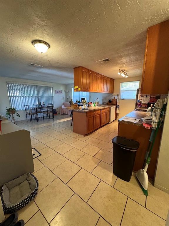 A kitchen with wood cabinets and tile flooring opens into a dining and living area — 8220 FOX HOLLOW DRIVE, PORT RICHEY, FL