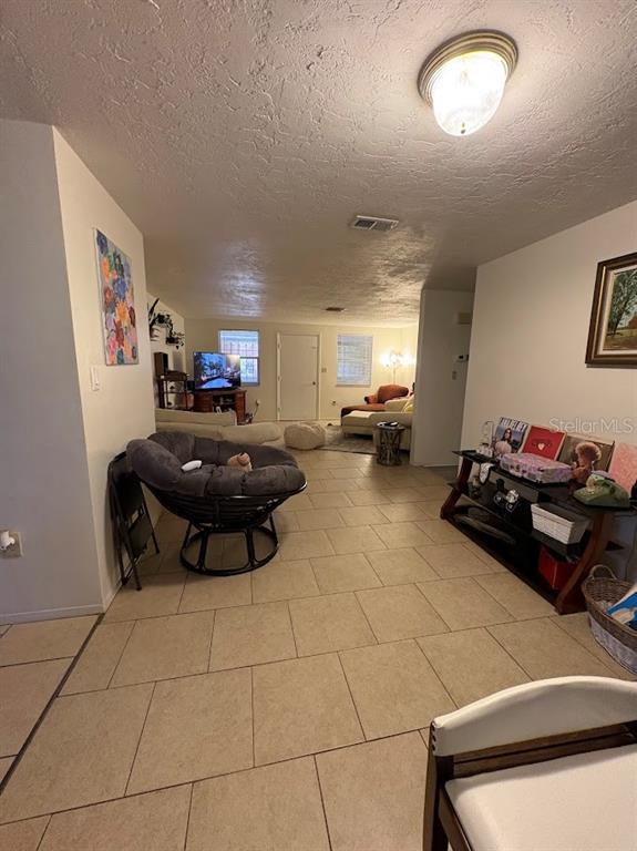 A living room features tile flooring, a papasan chair, and a media console — 8220 FOX HOLLOW DRIVE, PORT RICHEY, FL