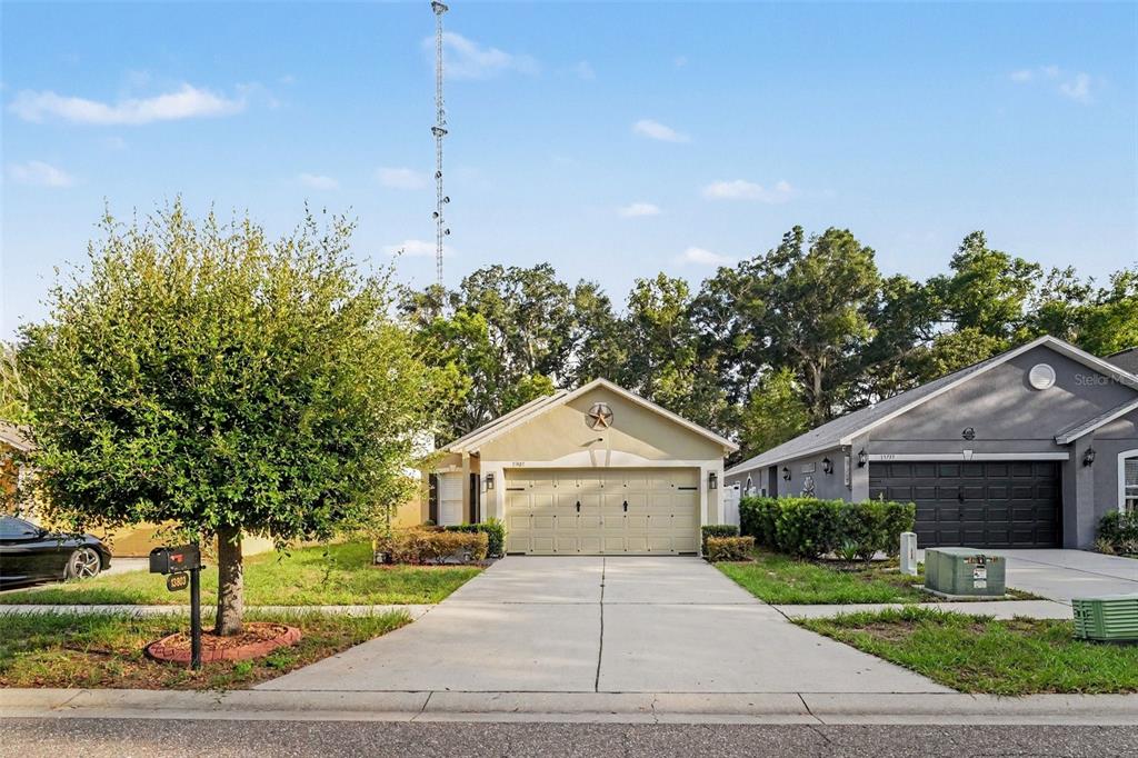 A tan single-story house with a two-car garage and a concrete driveway — 13803 GENTLE WOODS AVENUE, RIVERVIEW, FL