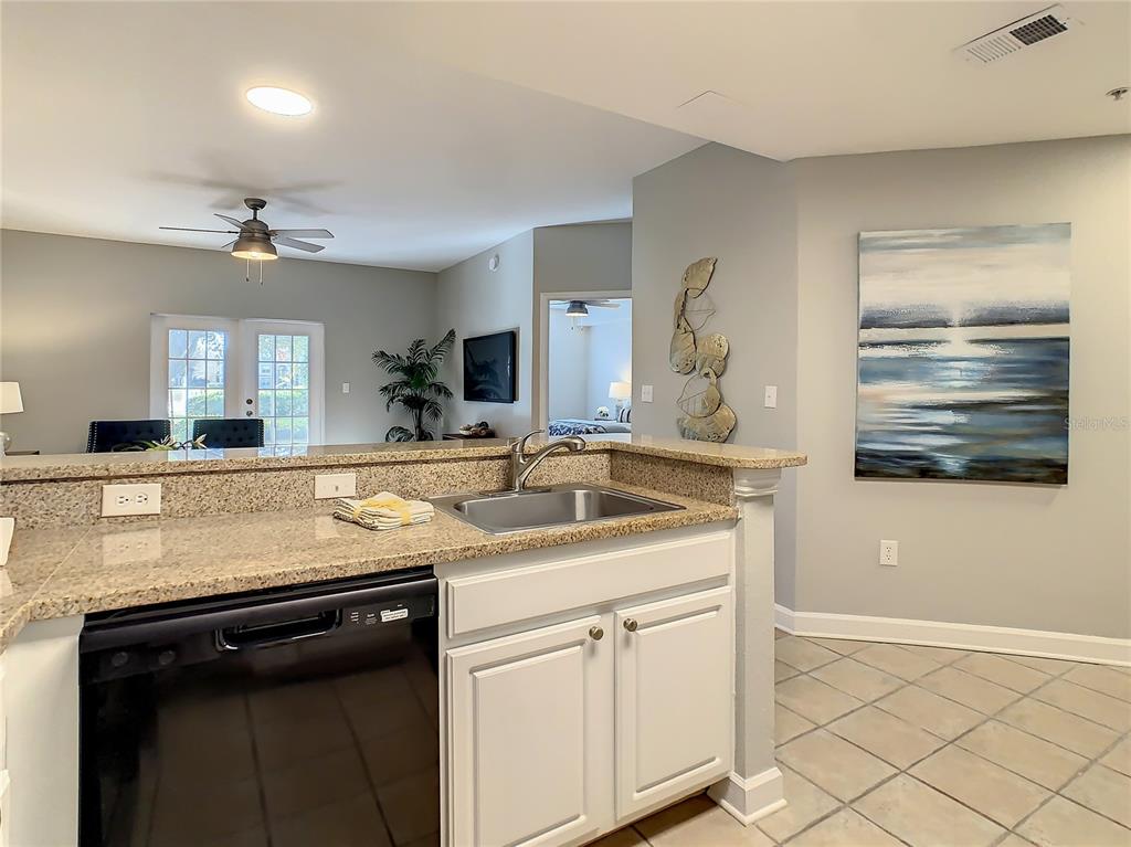 A kitchen sink and dishwasher are set into a granite countertop in this open-concept home — 7503 ATLANTIS WAY UNIT G103, KISSIMMEE, FL