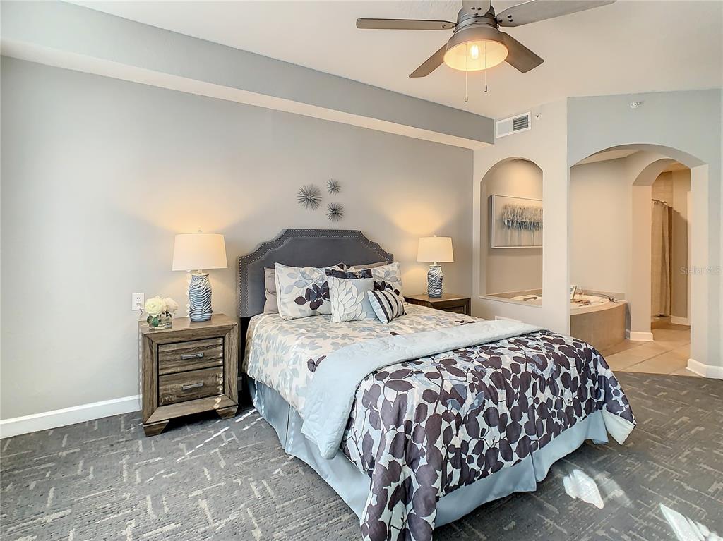 A bedroom features a bed with patterned bedding, two nightstands, and an adjacent bathroom alcove — 7503 ATLANTIS WAY UNIT G103, KISSIMMEE, FL