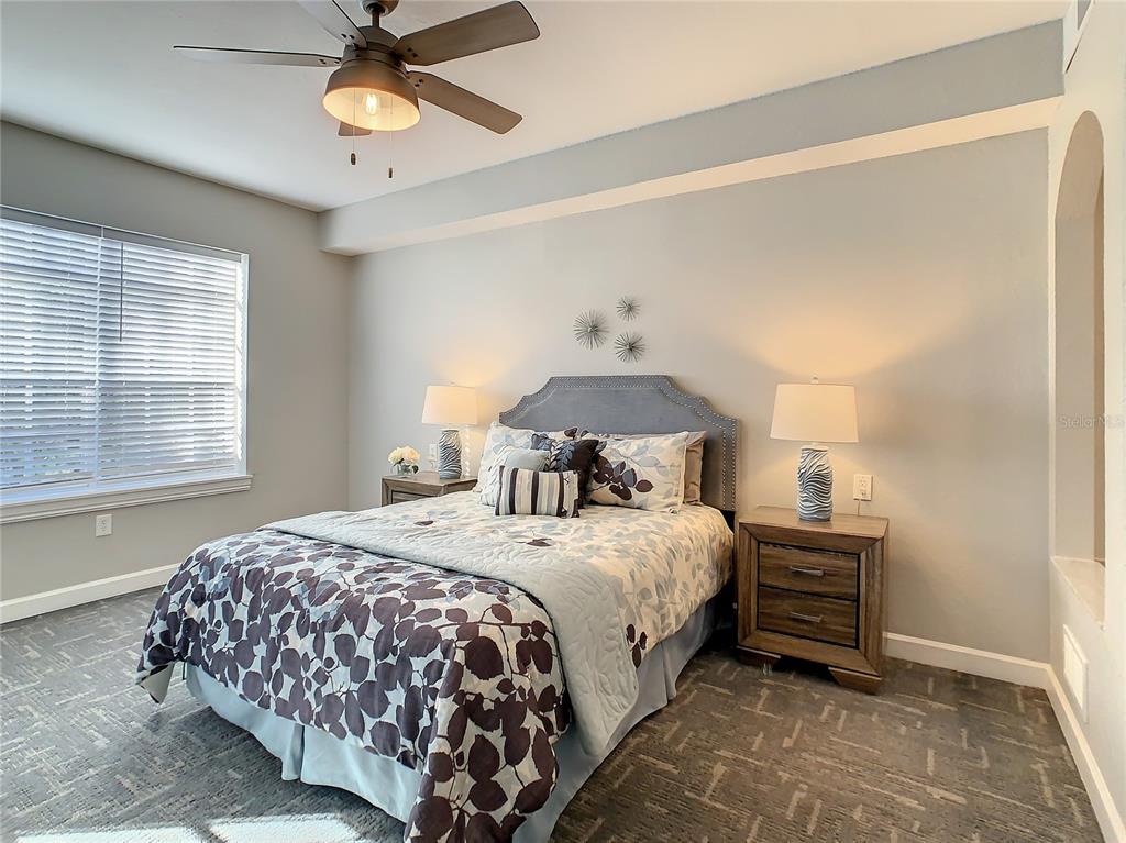 A bedroom features a bed with patterned bedding, two nightstands with lamps, and a ceiling fan — 7503 ATLANTIS WAY UNIT G103, KISSIMMEE, FL