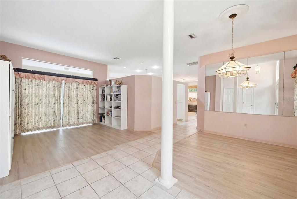 A living and dining area features light wood-look flooring, a central white column, and mirrors — 184 PINE STREET, HOMOSASSA, FL