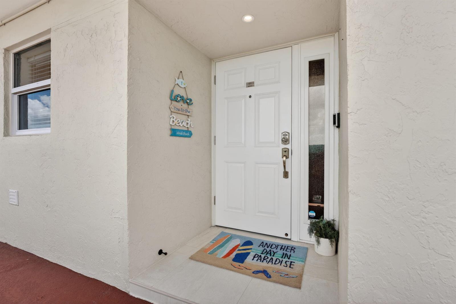 A white front door with a side window and a beach-themed welcome mat — 1523 E Hillsboro Boulevard # 631, Deerfield Beach FL 33441, DEERFIELD BEACH, FL