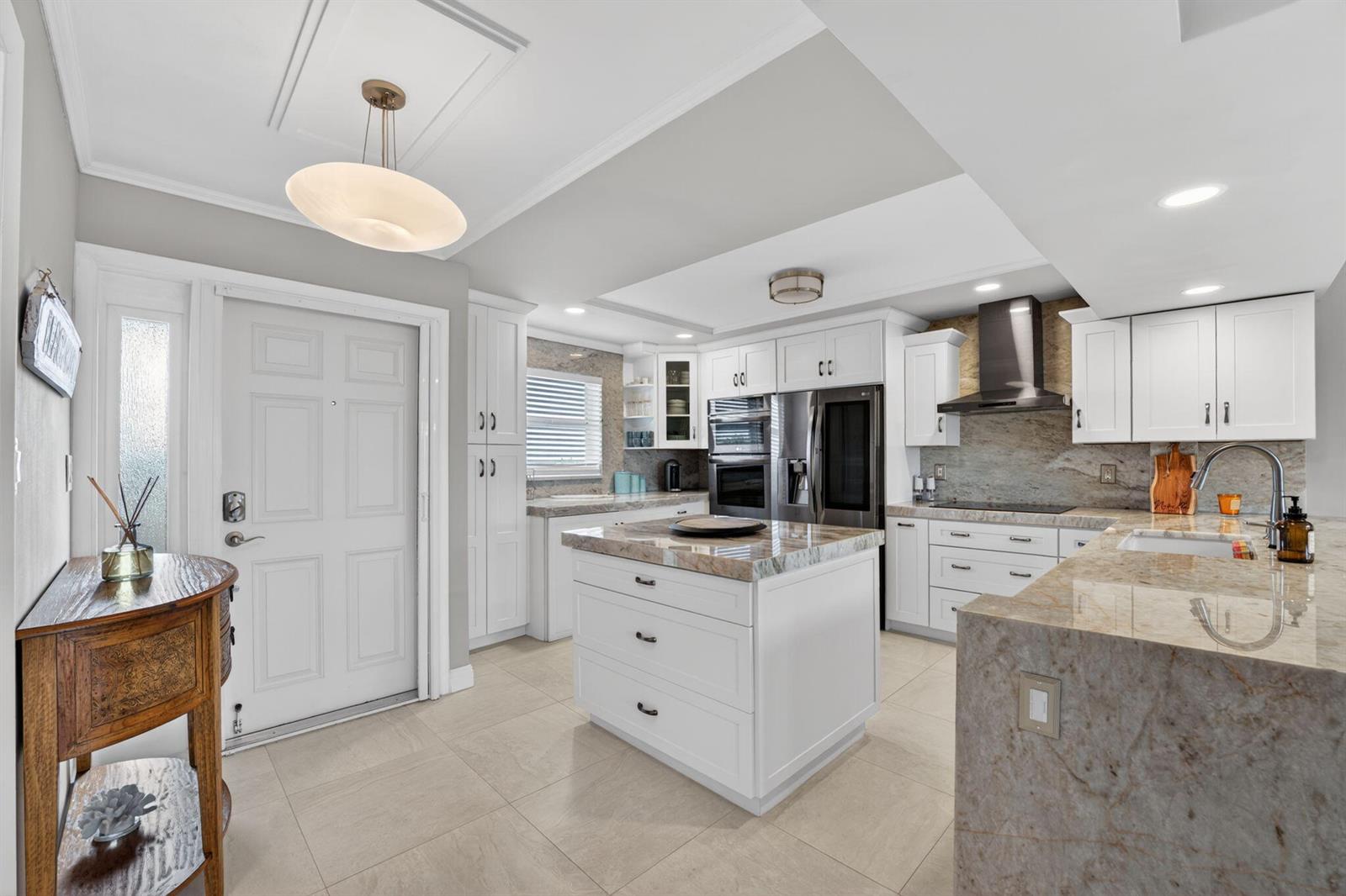 A kitchen features white cabinetry, a central island, and granite countertops with tile flooring — 1523 E Hillsboro Boulevard # 631, Deerfield Beach FL 33441, DEERFIELD BEACH, FL