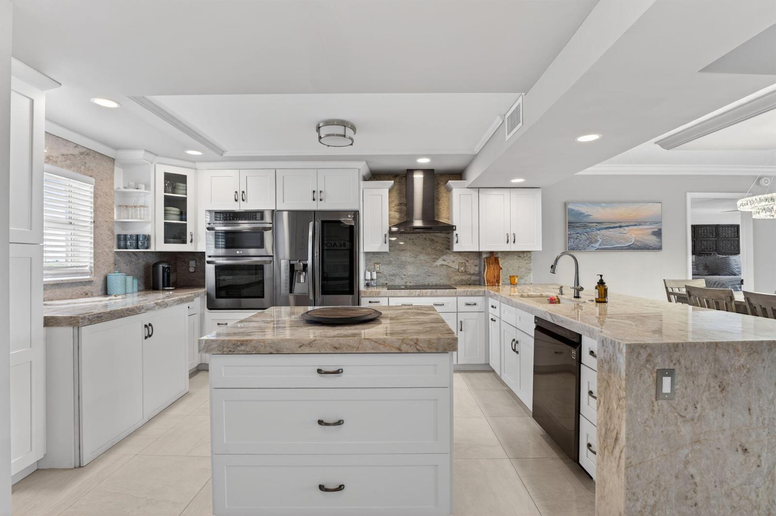 A white kitchen features a large stone-topped island, stainless steel appliances, and light tile flooring — 1523 E Hillsboro Boulevard # 631, Deerfield Beach FL 33441, DEERFIELD BEACH, FL