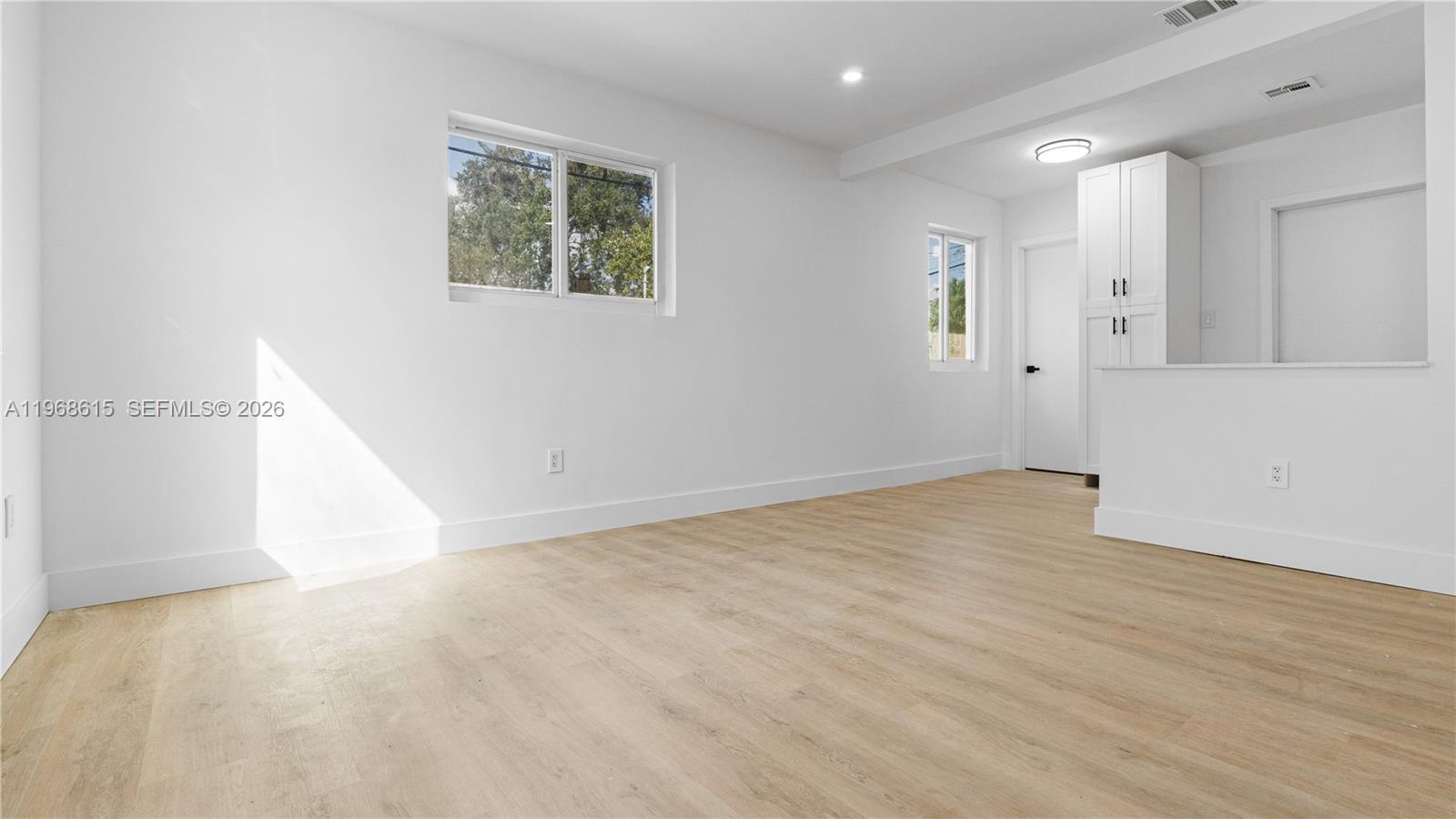 This is a digitally staged living room featuring a white sofa, coffee tables, and wall art — 1735 NW 126th St, Miami FL 33167, MIAMI, FL