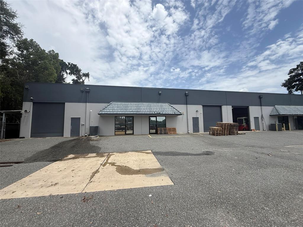 A single-story commercial building features gray walls, roll-up bay doors, and a paved parking lot — 810 NW 25TH AVENUE UNIT 100, OCALA, FL