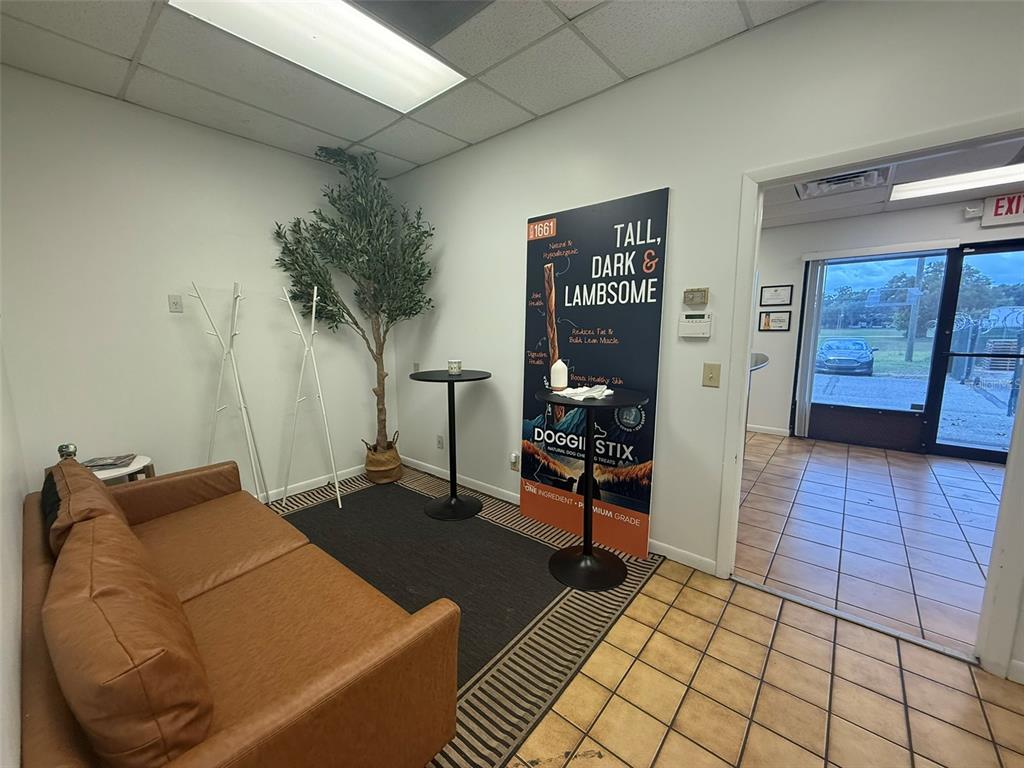A waiting area features a brown leather sofa, a tall advertising sign, and a potted tree — 810 NW 25TH AVENUE UNIT 100, OCALA, FL