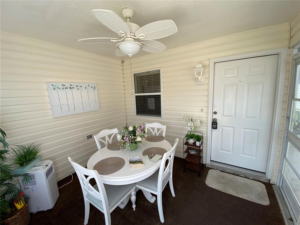 A sunroom features a white dining set, a ceiling fan, and a white entry door — 1672 DURAN DRIVE, THE VILLAGES, FL