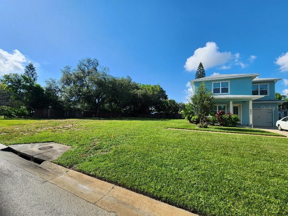 A vacant, grassy residential lot sits next to a two-story light blue house — 24TH AVENUE N, ST PETERSBURG, FL