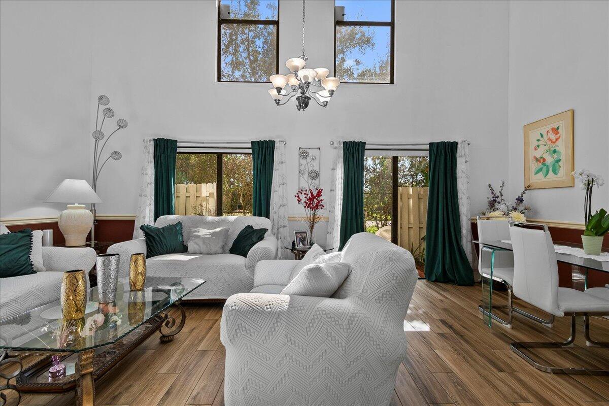 A living room with high ceilings, a glass coffee table, and white slipcovered furniture — 605 Maplewood Drive, FL 33415, FL