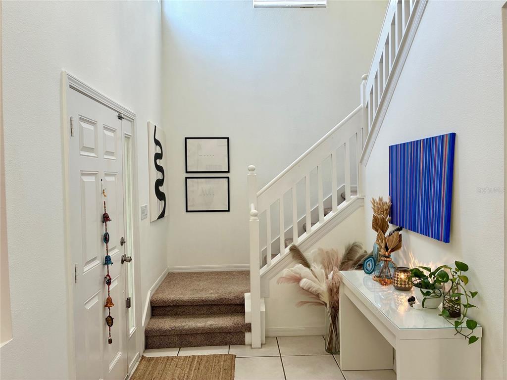 An entryway features a staircase with white railings, tile flooring, and a console table — 8026 CARRIAGE POINTE DRIVE, GIBSONTON, FL