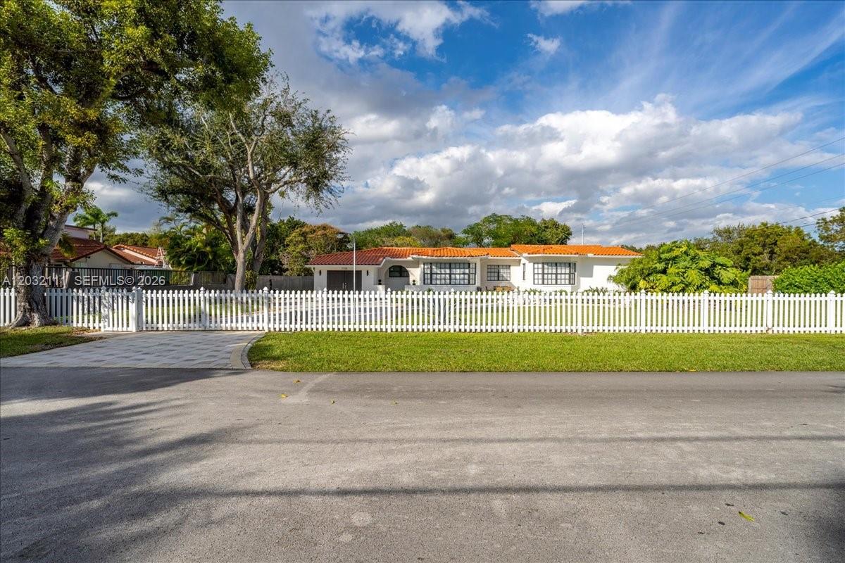 A white single-story house with a red tile roof sits behind a white picket fence — 7705 SW 66th St # 0, Miami FL 33143, MIAMI, FL