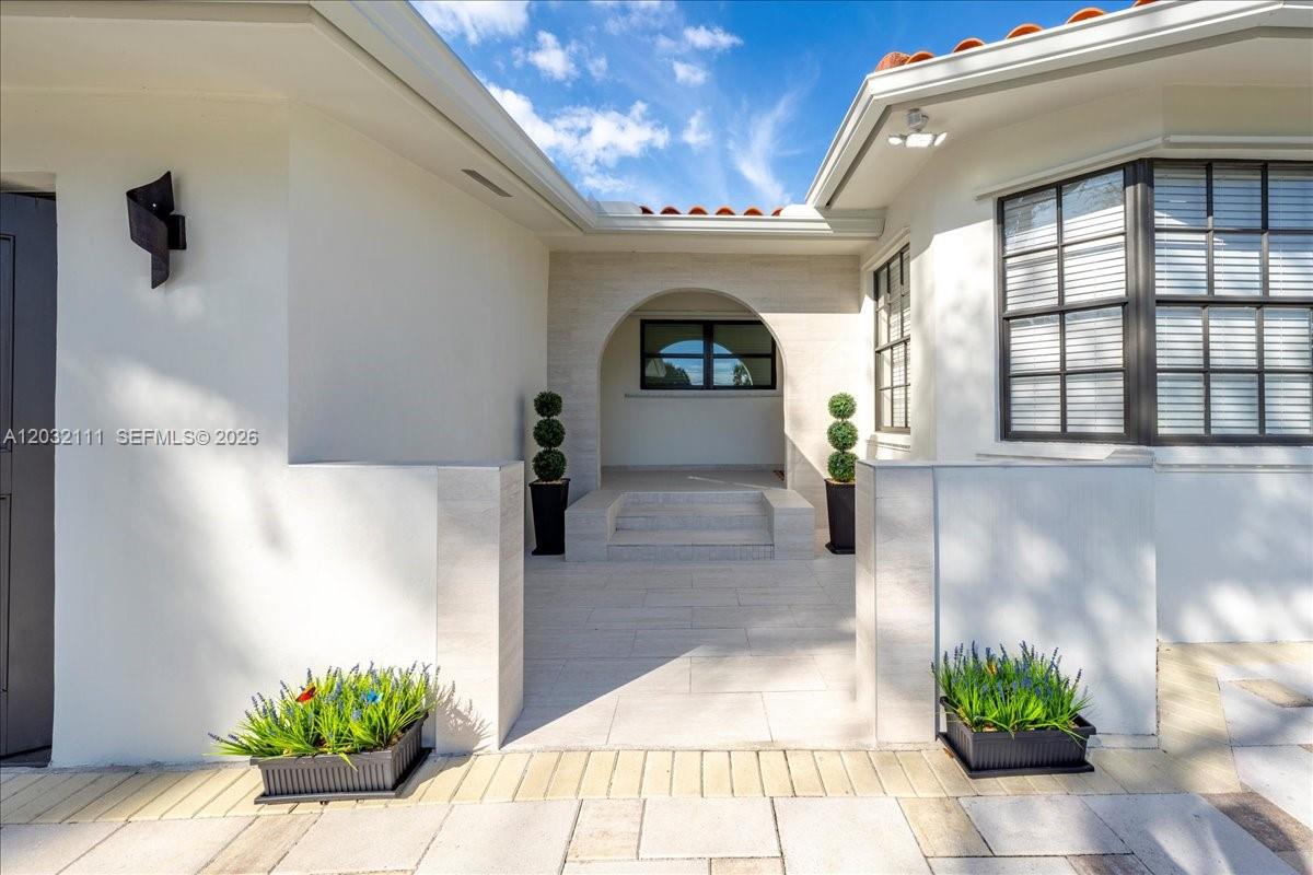 The exterior entrance features a paved courtyard, a white arched doorway, and two potted topiaries — 7705 SW 66th St # 0, Miami FL 33143, MIAMI, FL