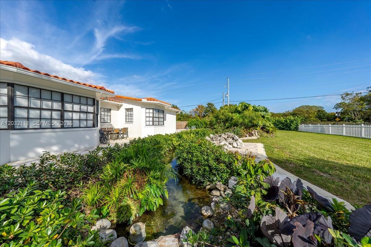A white house exterior features a small stone-lined water feature and lush landscaping — 7705 SW 66th St # 0, Miami FL 33143, MIAMI, FL