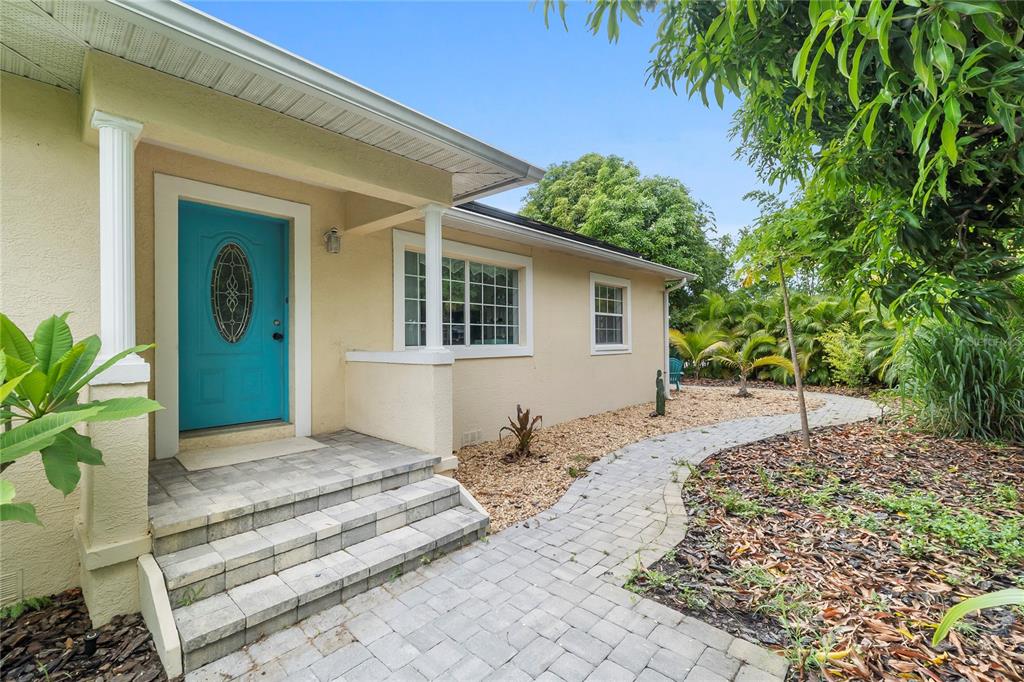 A paved walkway leads to the front entrance of a house with a turquoise door — 1701 38TH AVENUE, ST PETERSBURG, FL