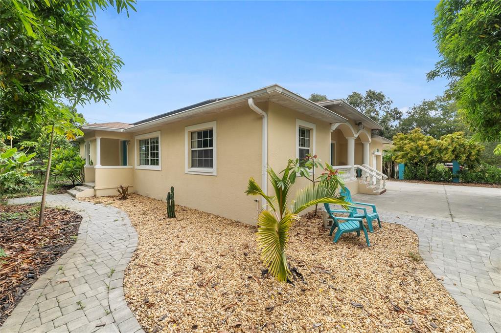 A tan house exterior features a stone walkway, gravel landscaping, and two blue patio chairs — 1701 38TH AVENUE, ST PETERSBURG, FL