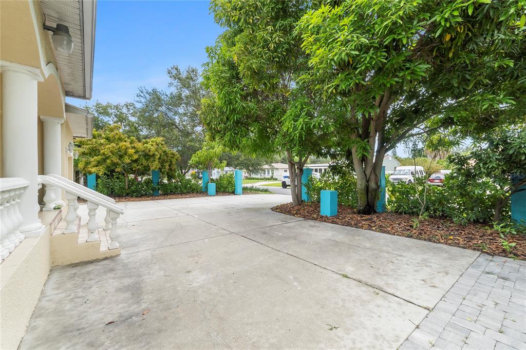 A concrete driveway leads to a house entrance with white railings and blue support pillars — 1701 38TH AVENUE, ST PETERSBURG, FL