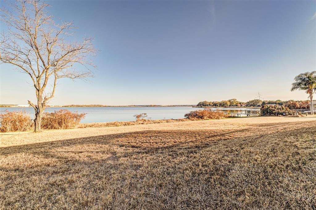 A grassy yard overlooks a calm lake with a bare tree and a palm tree — 411 EDGEWATER DRIVE, POLK CITY, FL