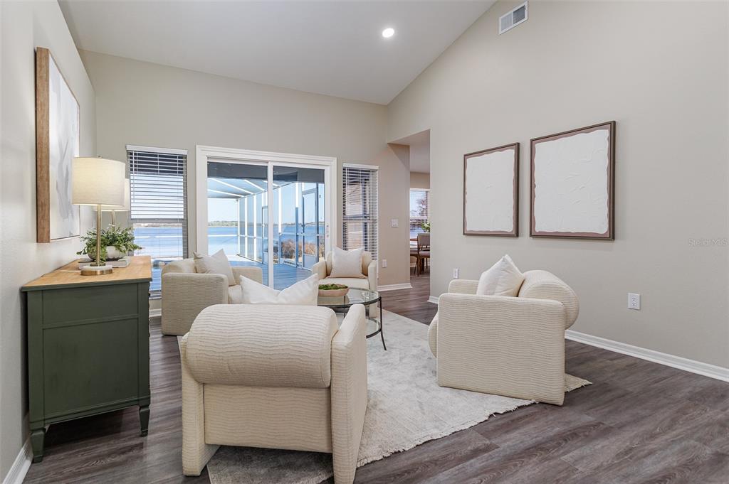 A living room with four cream armchairs, a glass coffee table, and a lake view — 411 EDGEWATER DRIVE, POLK CITY, FL