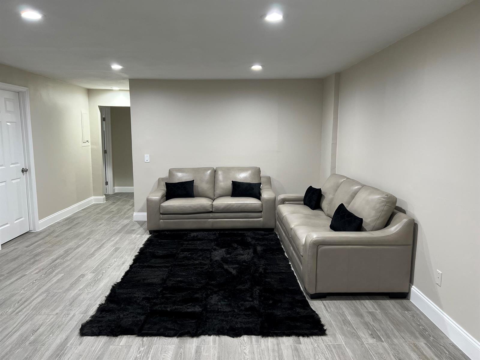 A living room features light gray flooring, beige walls, two leather sofas, and a black rug — 601 NW 2nd Street, Delray Beach FL 33444, DELRAY BEACH, FL