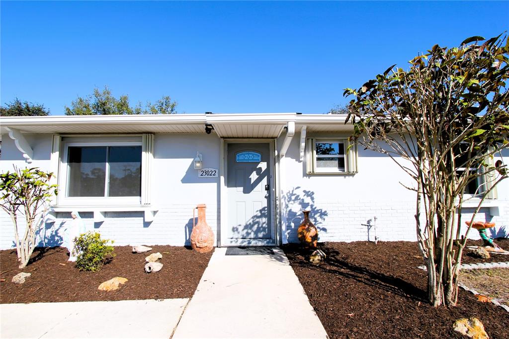 A single-story house with a light gray brick exterior, a front door, and two windows — 23022 MCNULTY AVENUE, PORT CHARLOTTE, FL