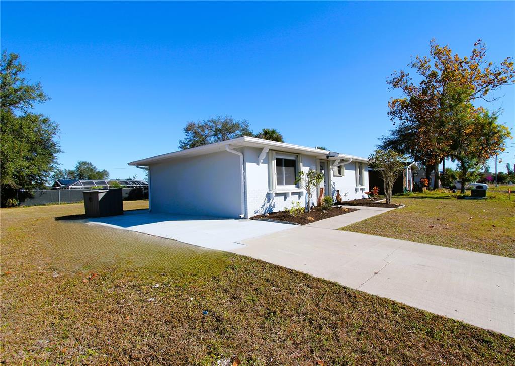 A single-story house with a light-colored exterior, a concrete driveway, and a large yard — 23022 MCNULTY AVENUE, PORT CHARLOTTE, FL