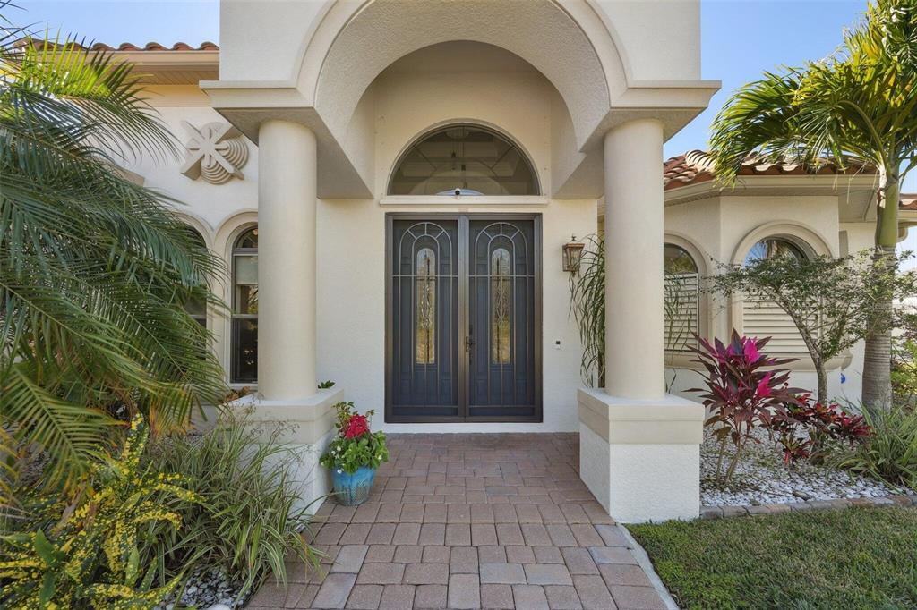 The front entrance features a double door with iron grilles under a stucco arched portico — 6557 LINO ROAD, NORTH PORT, FL