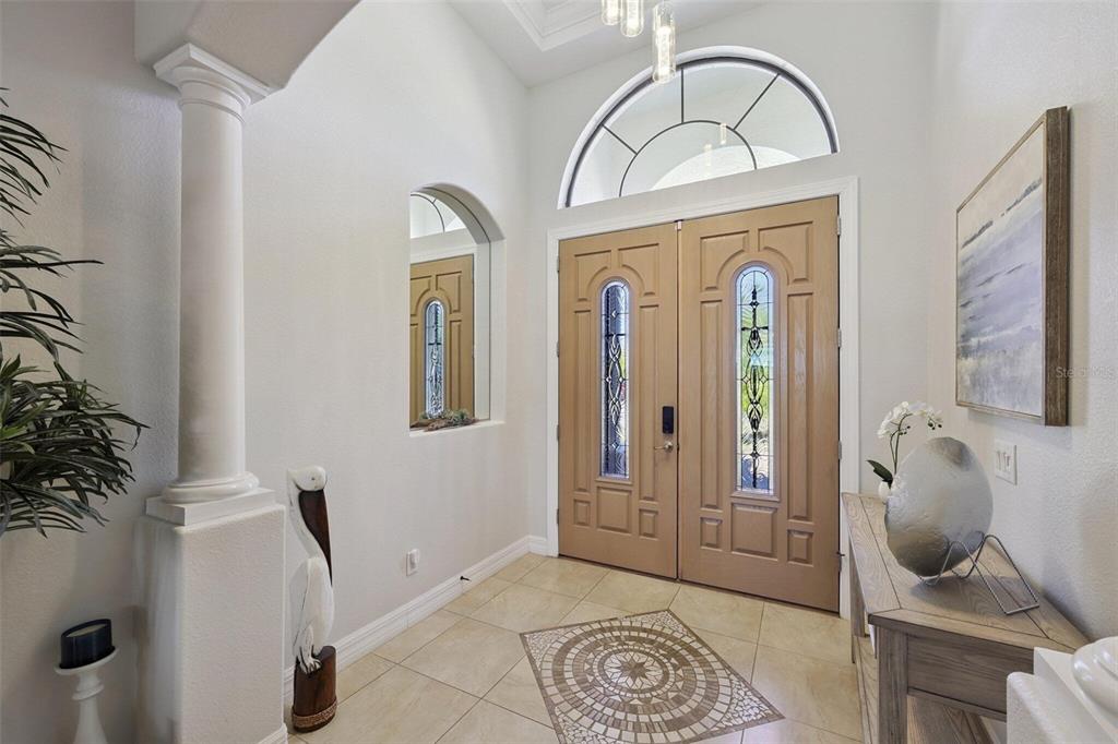 An entryway features double wood doors with glass inserts, tile flooring, and a decorative column — 6557 LINO ROAD, NORTH PORT, FL