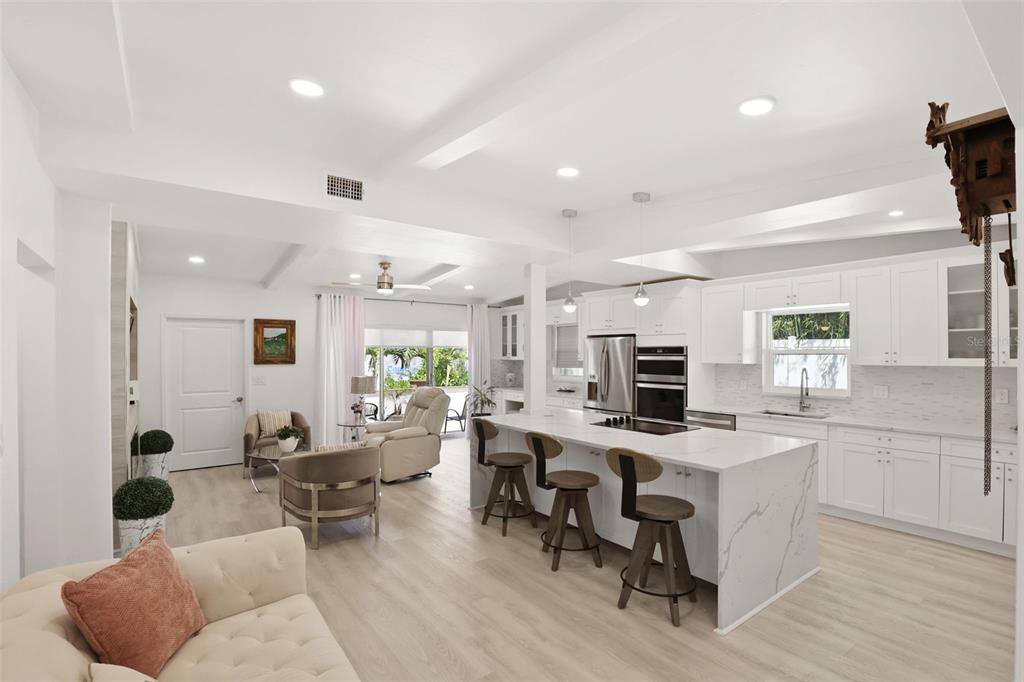 A bright, open-concept kitchen and living area featuring white cabinetry, a marble-topped island, and flooring — 25 SANDPIPER ROAD, TAMPA, FL