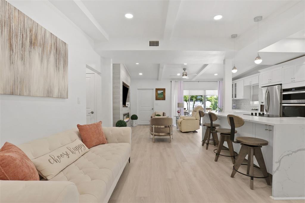 A bright open-concept living room and kitchen with light wood floors and white cabinetry — 25 SANDPIPER ROAD, TAMPA, FL